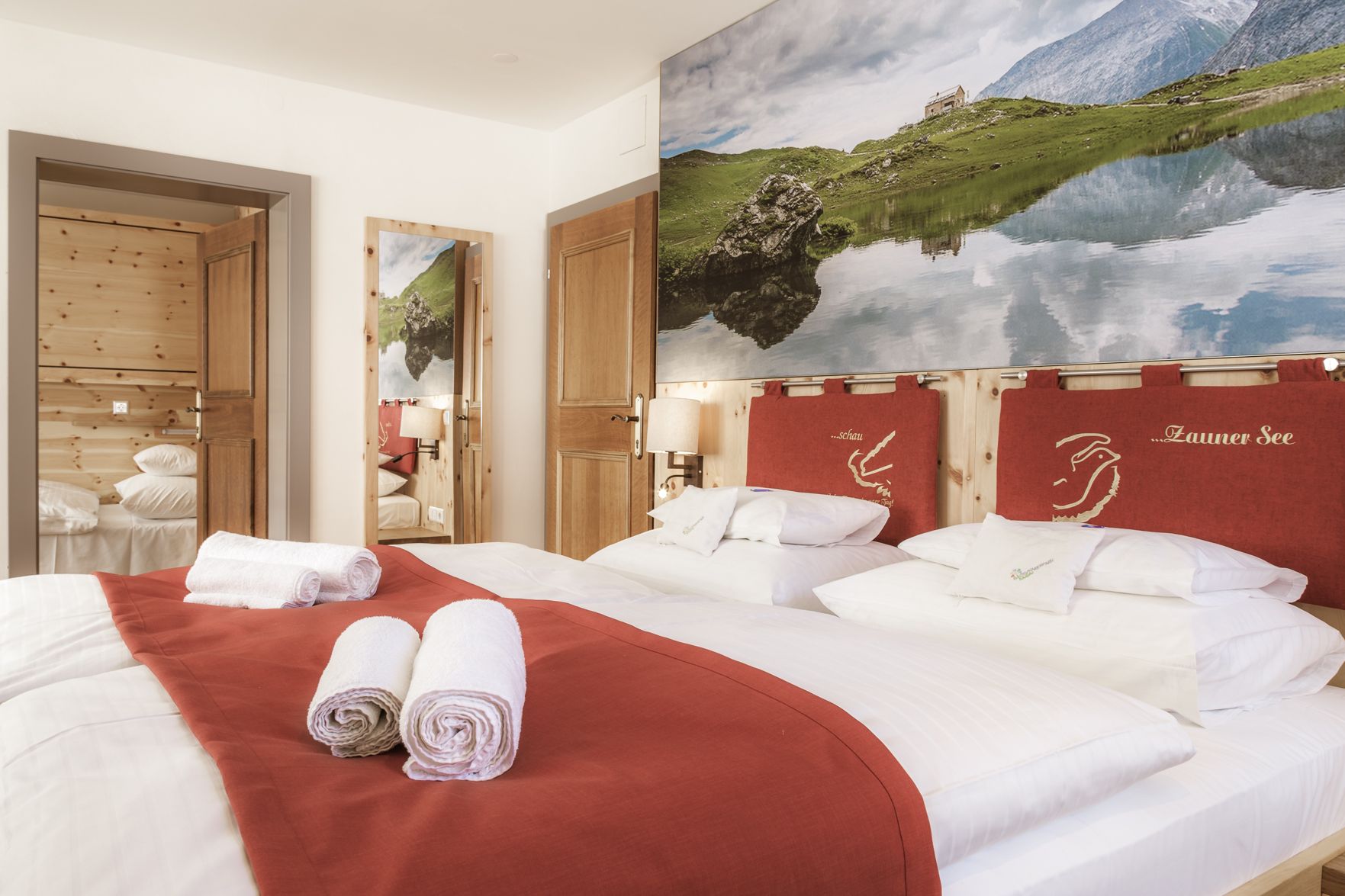 Gemütliches 3-Sterne-Familienzimmer mit Bergdekor und roten Akzenten in Mauterndorf, Salzburger Lungau.