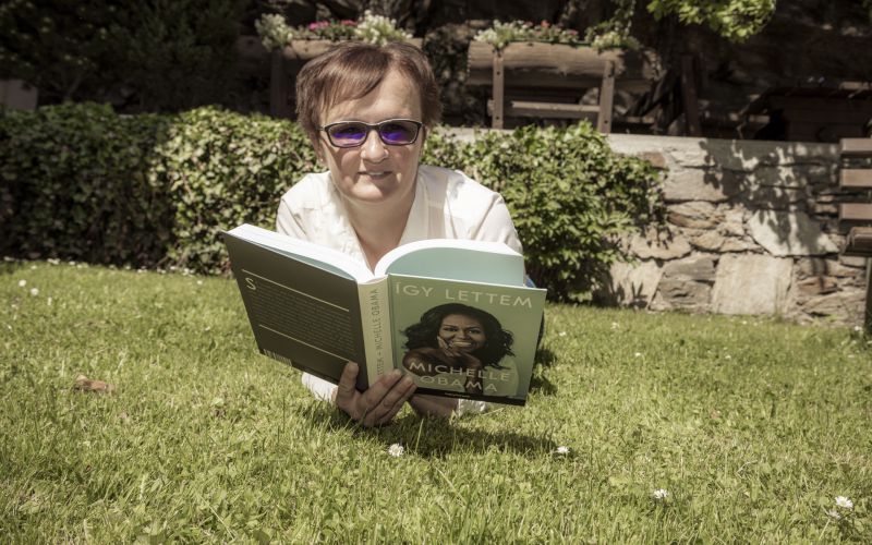 Person liegt im Gras und liest Michelle Obamas Buch im Garten.