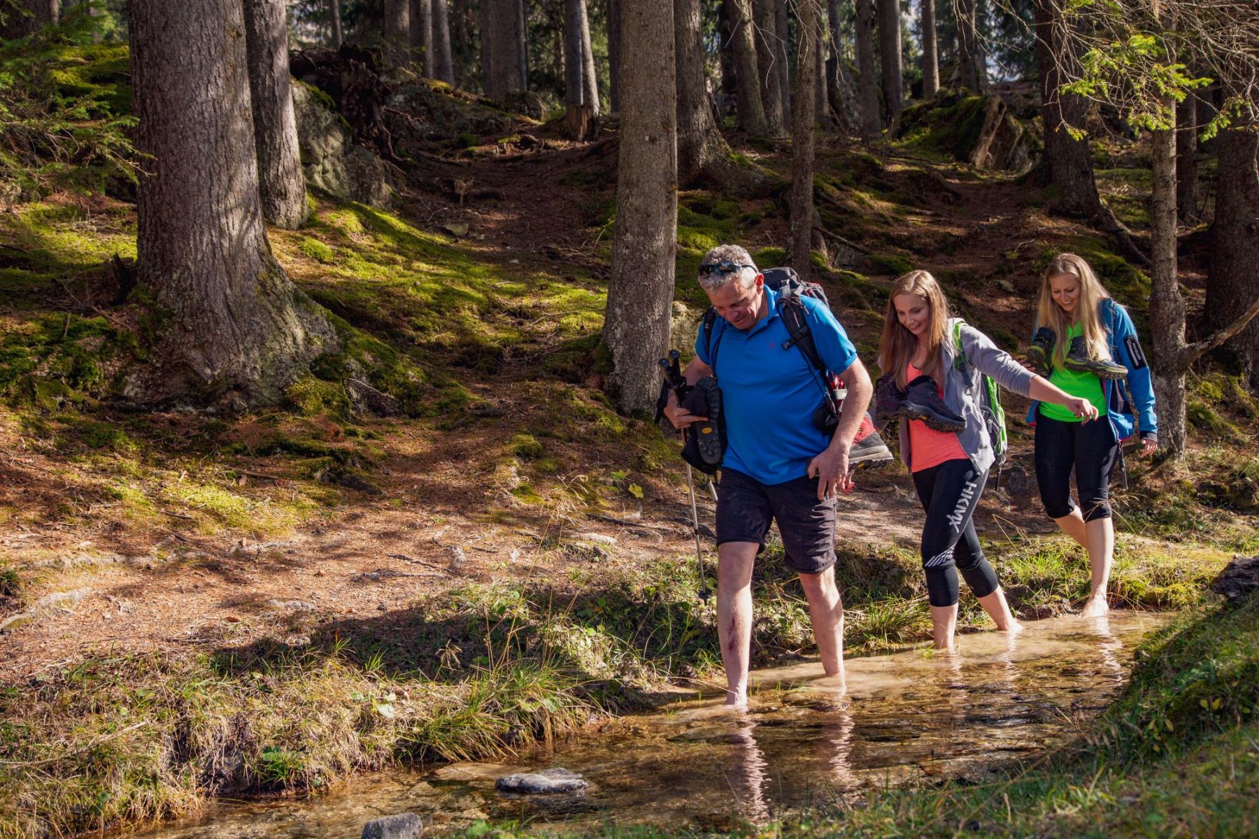 Familie überquert einen Bach in einem Waldgebiet, wandern in der Region Salzburger Lungau.