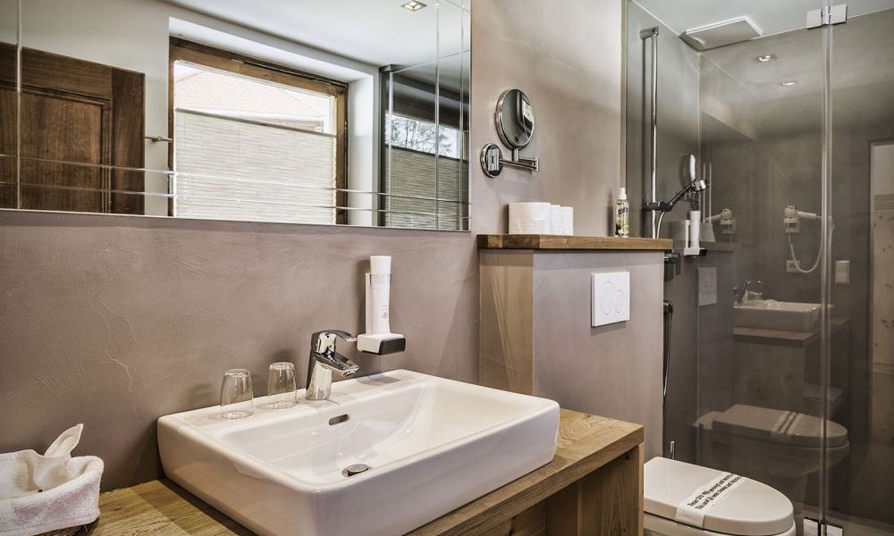 Modernes Badezimmer mit Holzelementen, Glasdusche und großem Spiegel.