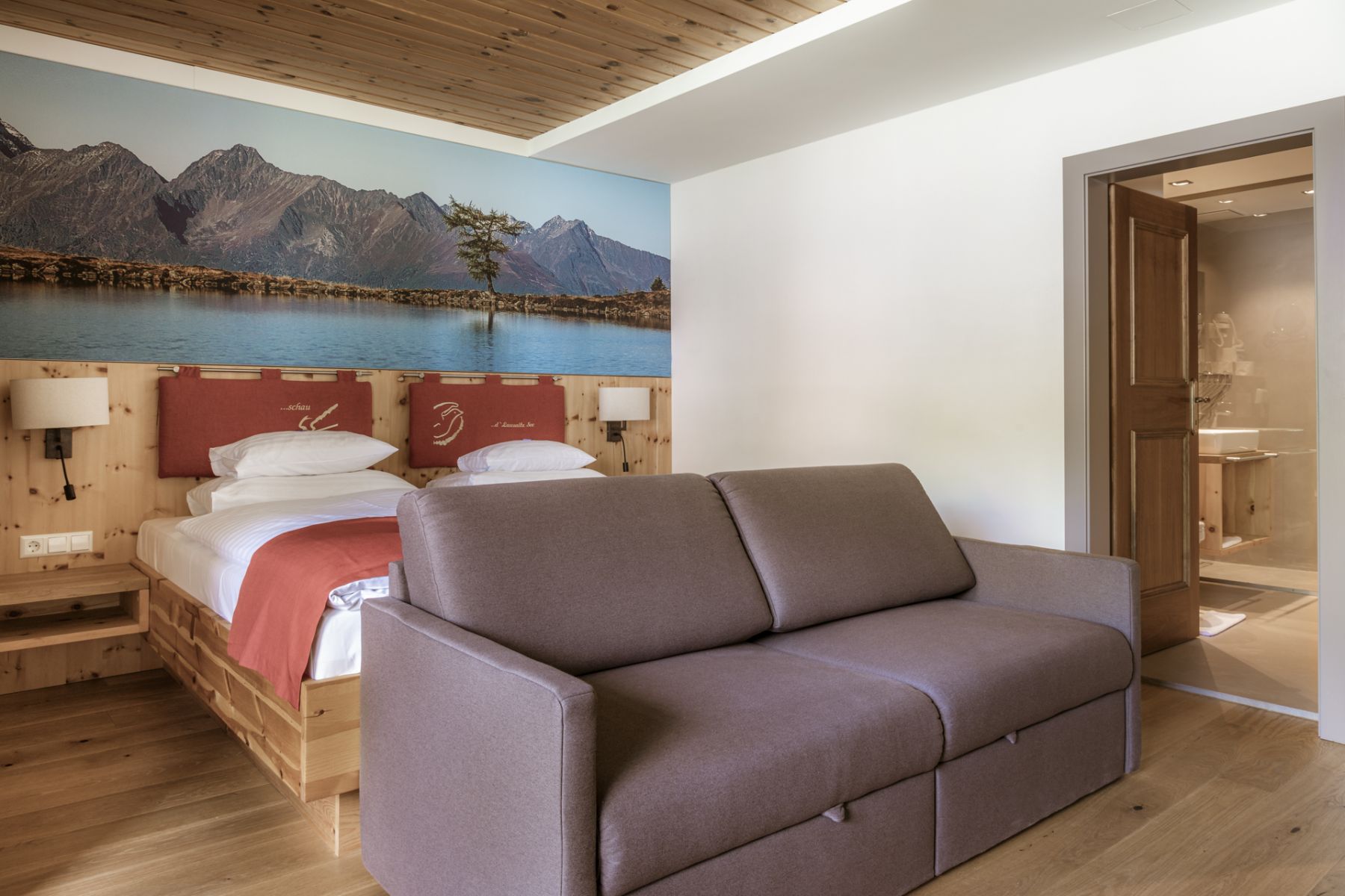 Zimmer einer Familienpension mit Doppelbett, Sofa, Bergbild, Bad in Mauterndorf, Salzburg.