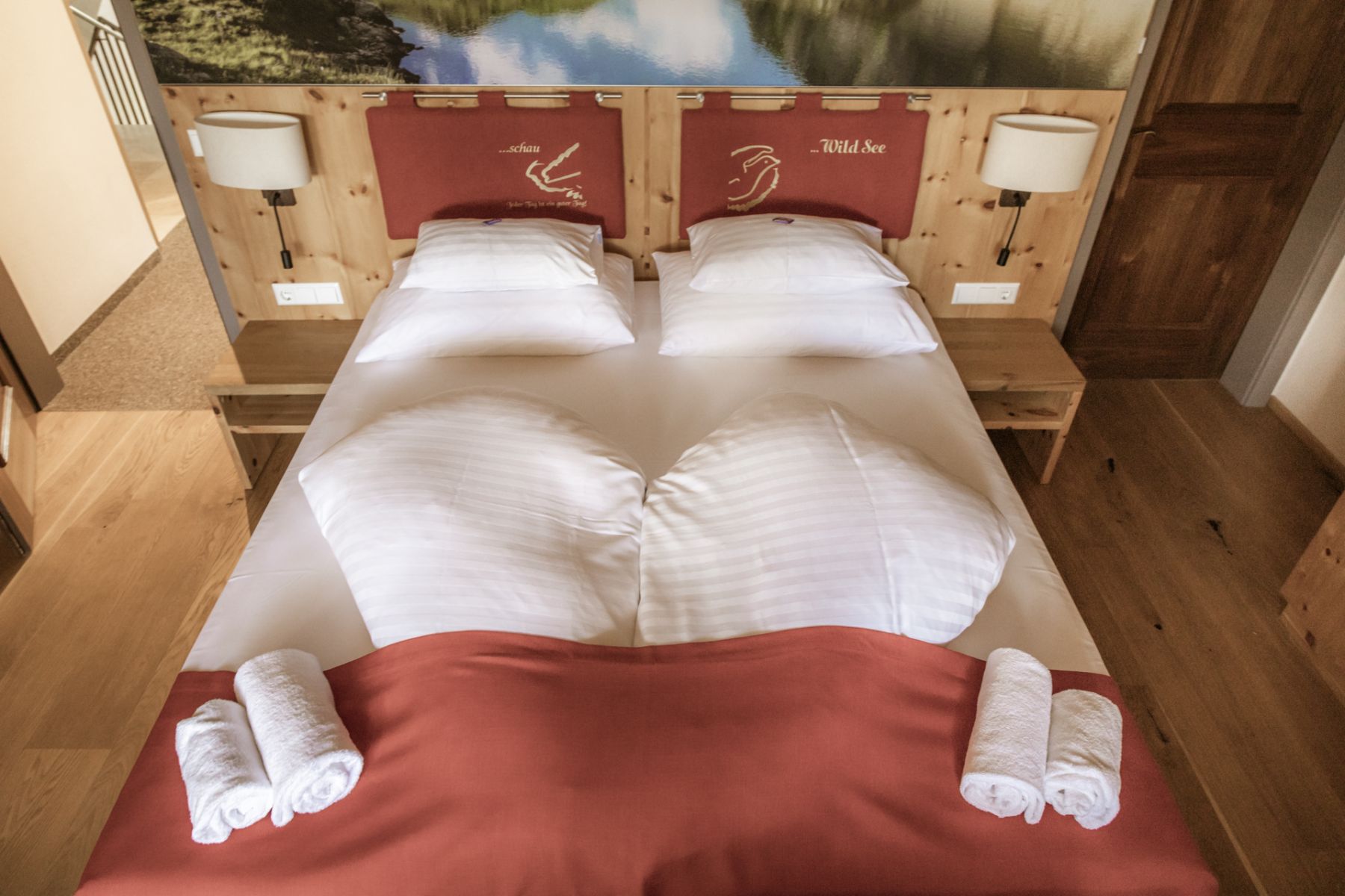Gemütliches Doppelbett mit roten Akzenten in einer Salzburger Familienpension.