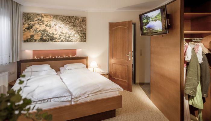 Gemütliches Hotelzimmer mit Doppelbett, Holzmöbeln und TV in Mauterndorf, ideal für Familienurlaub.